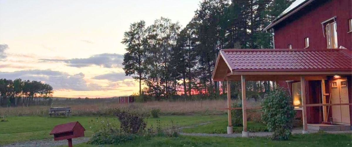 rasmusbyn-lss-boende-örebro-natur-hus.jpg Fält och ett av husen på Rasmusbyns LSS-boende utanför Örebro.